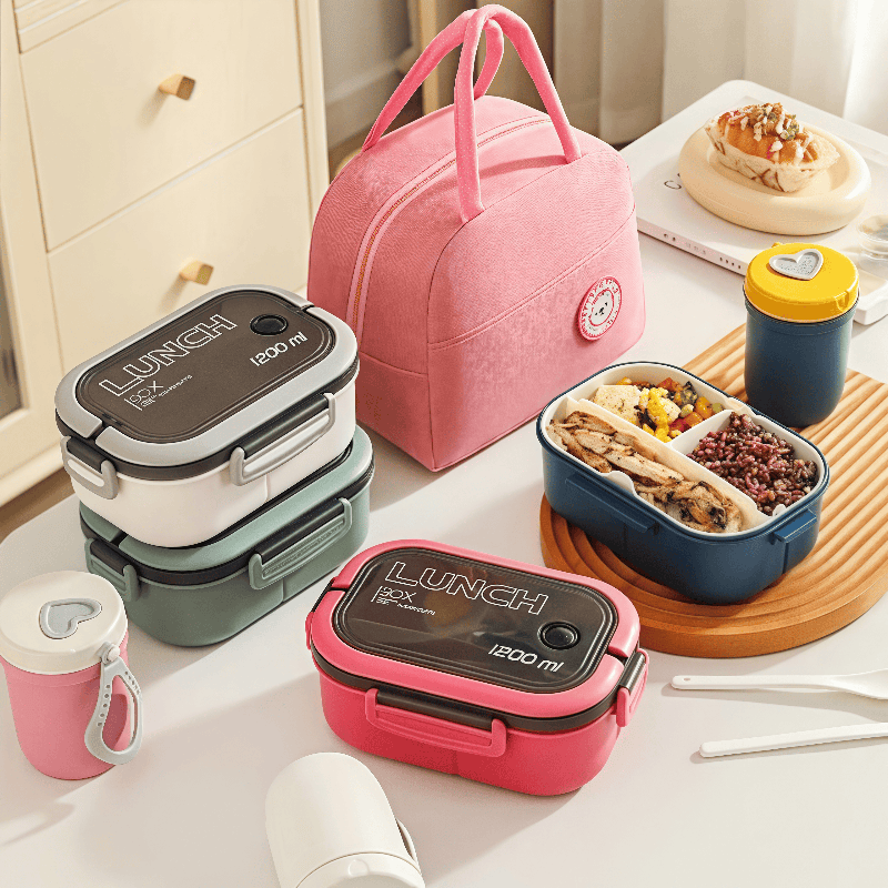 A pink lunch bag and various colored bento type lunch boxes on a table.