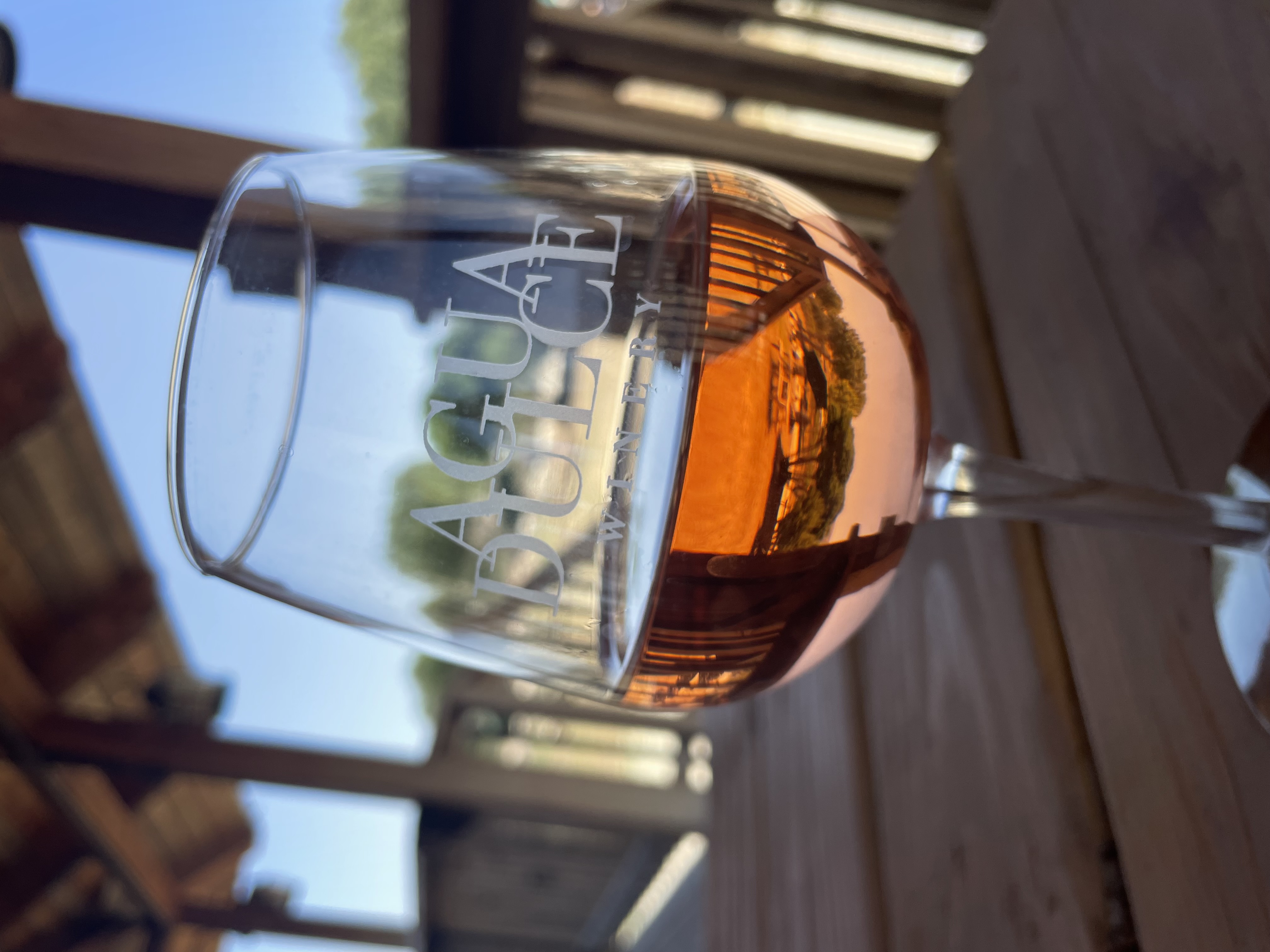 Close up image of a glass of Agua Dulce's rose with the winery grounds reflected in the glass