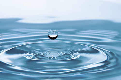 Water droplet creating ripples on water surface